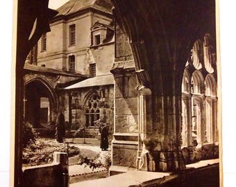 May include: A vintage travel poster featuring a black and white photograph of the Saint Wandrille Abbey cloister in Normandy, France. The image is framed by stone arches, with the text SAINT WANDRILLE (NORMANDIE) CLOITRE DE L'ABBAYE and FRANCE.