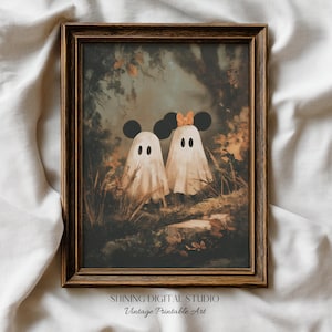 May include: A framed vintage print featuring two ghost figures with Mickey Mouse ears in a forest setting. The ghosts are draped in white sheets with black eyes. The print has a brown wooden frame and the text "SHINING DIGITAL STUDIO Vintage Printable Art".