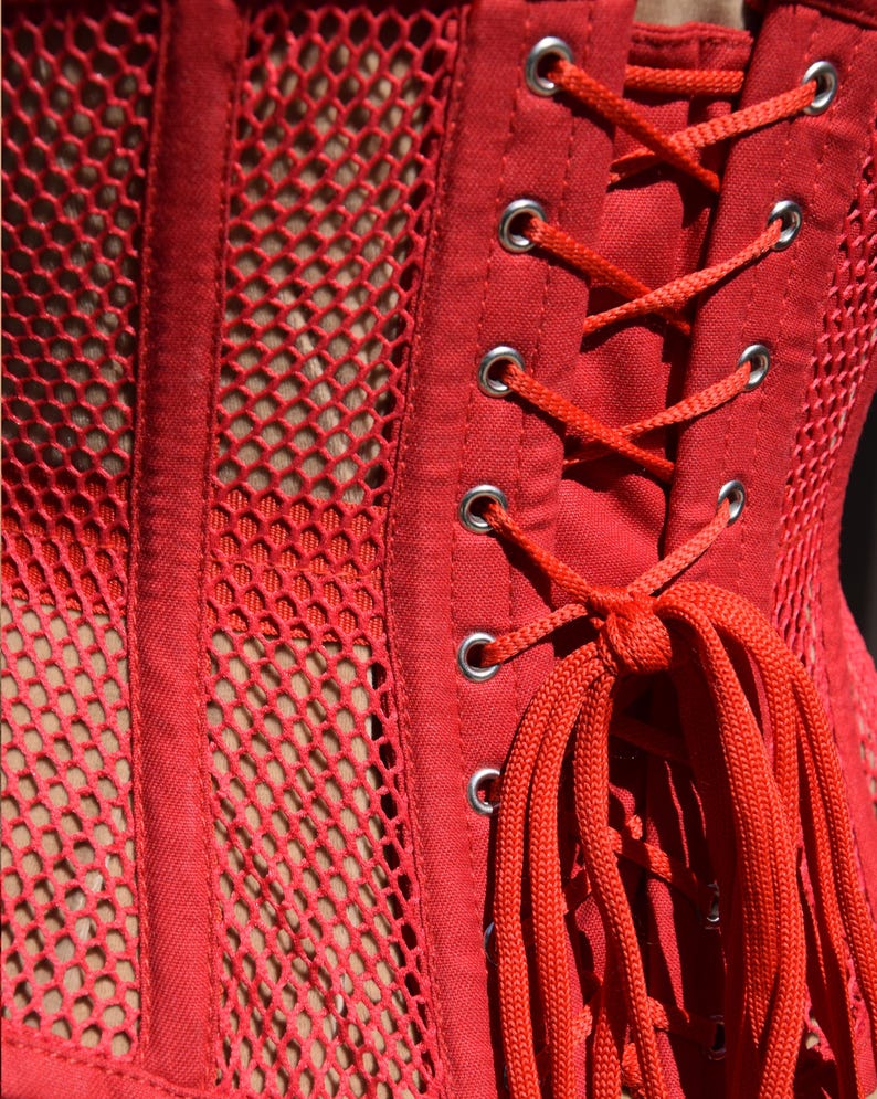 May include: Red corset with a mesh panel and a lace-up back. The corset is made of a soft, stretchy fabric and has a comfortable fit.