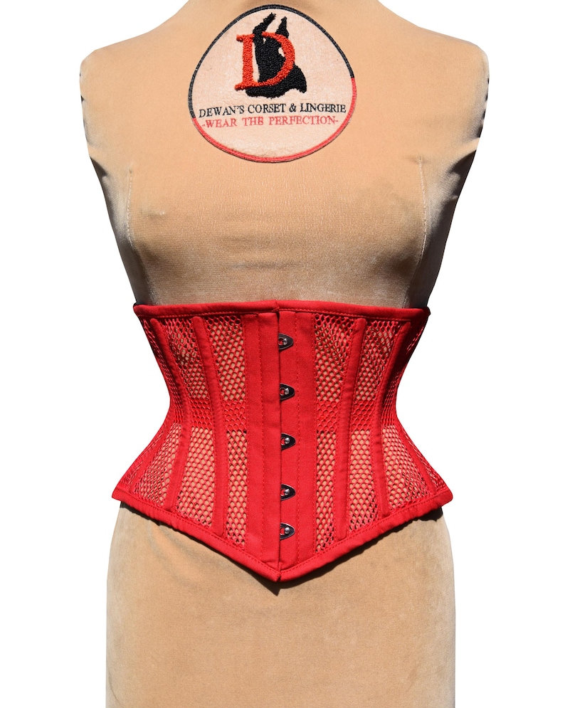 May include: Red mesh corset with a black busk closure and a label that reads "Dewan's Corset & Lingerie - Wear the Perfection - "