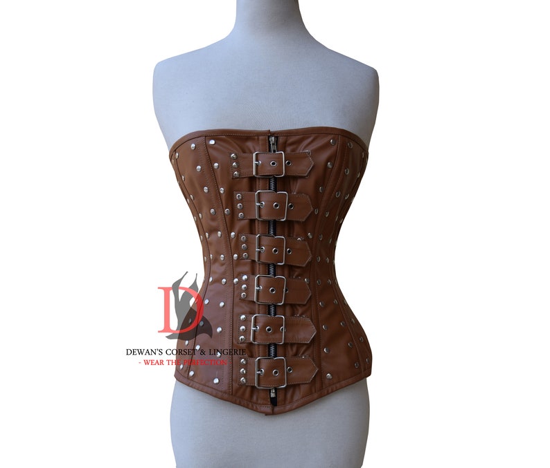 May include: A brown leather corset with silver buckles and studs. The corset has a strapless design and a pointed bottom.
