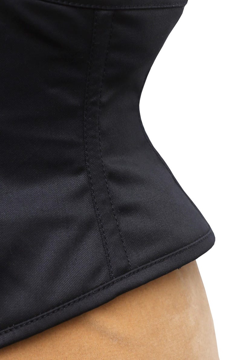 May include: A black corset with a smooth, satin-like finish. The corset has a fitted, hourglass shape and features a seam down the center back.
