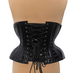Puede incluir: Cors&eacute; de charol negro con lazada en la espalda. El cors&eacute; tiene una estructura con varillas y un acabado liso y brillante.