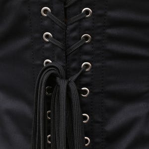 May include: Black corset with a lace-up back and silver eyelets. The corset has a satin finish and is tied with black cords.