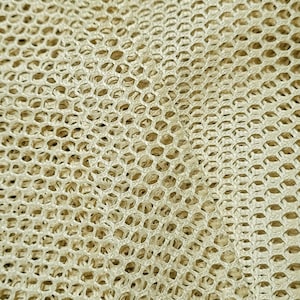 May include: Close-up of a beige mesh fabric with a woven pattern. The fabric is textured and has a slightly rough surface.