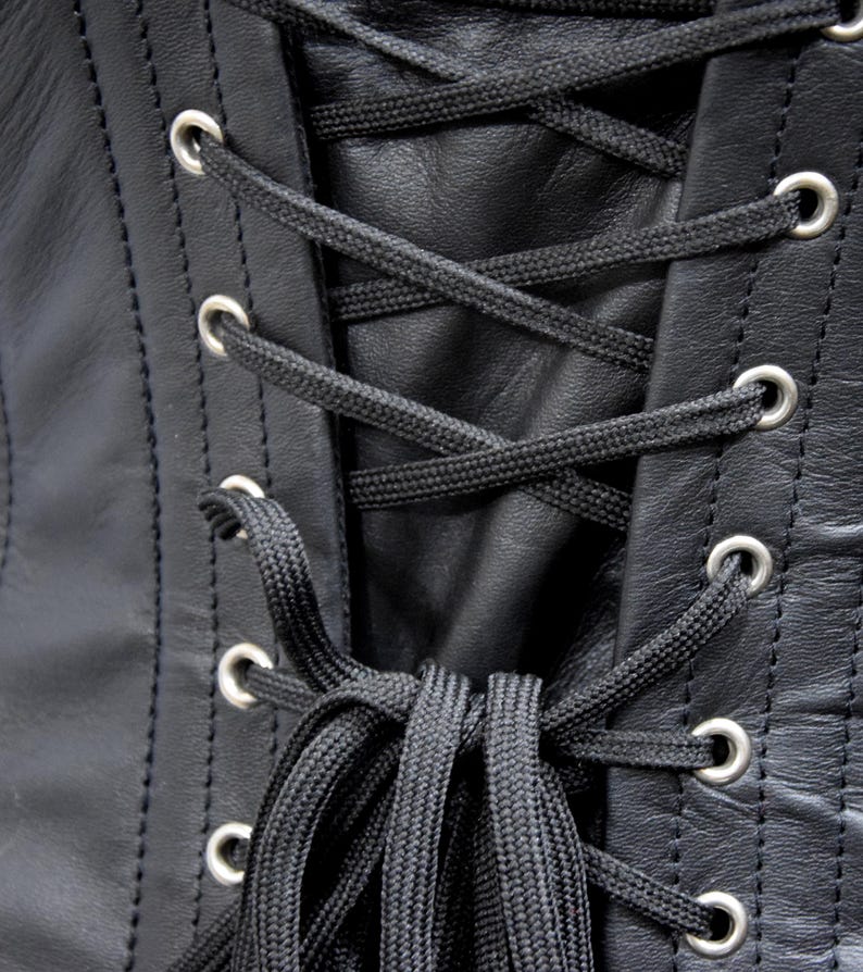 May include: Close-up of black leather with silver eyelets and black laces. The laces are tied in a knot at the bottom.