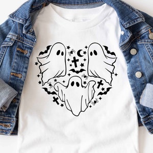 May include: White t-shirt with a black and white graphic of ghosts and other Halloween symbols in a heart shape.