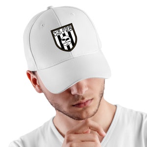 May include: White baseball cap with a black and white logo that says "We Are United" with a black eagle and the words "Warriors 2020" in gold.