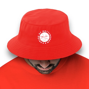 May include: A red bucket hat with a white embroidered logo that says "Pride of Nottingham" with a stylized image of a tree and a winding path.