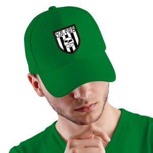 May include: A green baseball cap with a black and white logo that says "We Are United" and a black eagle with the words "Warriors 2002" underneath.