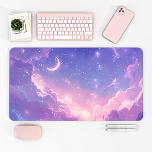 May include: A rectangular mouse pad with a dreamy sky design featuring a crescent moon, stars, and clouds in shades of purple, pink, and blue. A pink keyboard, phone, and mouse are on the white surface.