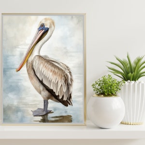 May include: A watercolour painting of a pelican with a light brown body and a long orange beak. The pelican is standing on a blue and white watercolour background.