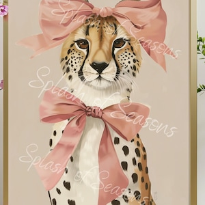 May include: Framed art print featuring a cheetah with a pink bow on its head and another around its neck. The cheetah has a tan coat with black spots and brown eyes. The background is a light beige color. The words "Splash of Seasons" are written across the image.