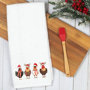 May include: White kitchen towel with a red, white, and green embroidered design of four chickens wearing Santa hats. The chickens are standing in a row and have different colored feathers.