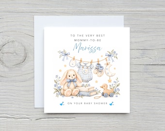 May include: A square greeting card featuring a watercolour illustration of a plush bunny, a baby onesie, booties, and a pull-along duck toy. The text reads: TO THE VERY BEST MOMMY-TO-BE Marissa ON YOUR BABY SHOWER, accented with blue hearts.
