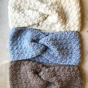 Pode incluir: Três faixas de cabeça de malha feitas à mão em creme, azul claro e castanho. Cada faixa de cabeça apresenta um design de nó torcido e um padrão de ponto texturizado. Estas faixas de cabeça confortáveis são perfeitas para manter as orelhas quentes.