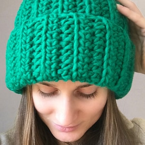 Peut inclure: Un bonnet en tricot vert vif. Le bonnet est fait avec un fil épais et a une coupe ample.