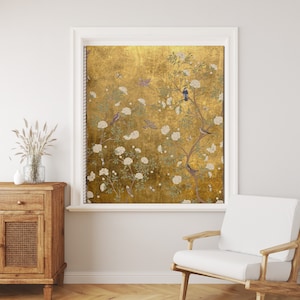 Puede incluir: Una persiana de ventana de color dorado con un patrón floral que presenta flores blancas y pájaros. La persiana está en una habitación con una pared blanca y una silla de madera.