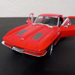 Puede incluir: Un coche modelo rojo Chevrolet Corvette de la d&eacute;cada de 1960 con las puertas abiertas. El coche tiene un parachoques cromado y una parrilla negra.