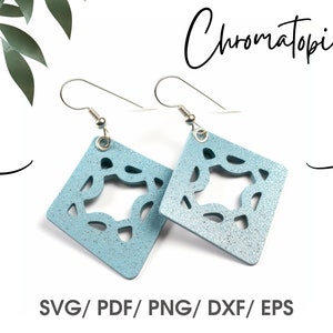 Pode incluir: Um par de brincos azuis claros com um design geométrico. Os brincos são feitos de um material brilhante e têm ganchos prateados.