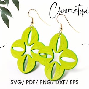 May include: A pair of green and yellow flower-shaped earrings with gold hooks. The earrings are made of leather and have a textured surface. The earrings are called "Chromatopía".