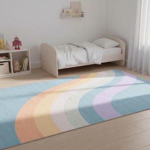 May include: A rectangular rug with a rainbow design in pastel colors, including blue, orange, yellow, and purple. The rug is placed on a light wood floor in a child's bedroom. A white bed and a small white shelf are also visible.