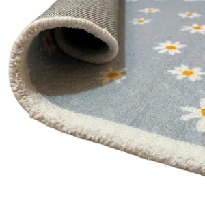 May include: A rolled-up rug featuring a light blue surface adorned with white daisies, each with a yellow centre. The rug has a white border and a grey backing.