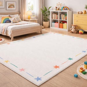 May include: A white rectangular rug with a border of colourful stars and lines. The rug is in a child's bedroom, with a bed, bedside tables, and a chest of drawers. Toys and decorations are also visible.