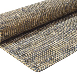 Puede incluir: Una alfombra enrollada con un patr&oacute;n tejido en tonos beige y azul marino. La alfombra est&aacute; hecha de una fibra natural y tiene un aspecto texturizado. El borde de la alfombra es visible, mostrando el grosor y el tejido.