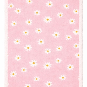 May include: A rectangular pink rug featuring a repeating pattern of white daisies with yellow centres. The rug has a white border. The design is simple and cheerful, suitable for a bedroom or nursery.