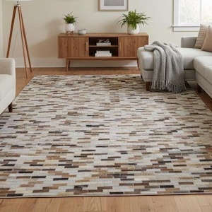 Puede incluir: Alfombra rectangular con un patrón geométrico en tonos beige, marrón y negro. La alfombra está colocada sobre un suelo de madera en un salón, con un sofá y un sillón visibles. Las dimensiones de la alfombra son en centímetros.