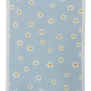 May include: A rectangular, pale blue rug with a white border. The rug features a pattern of white daisies with yellow centres. The daisies are evenly spaced, creating a cheerful design. The rug's dimensions are in centimetres.