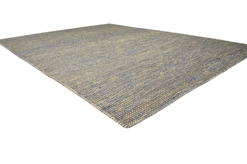 Puede incluir: Una alfombra rectangular con textura tejida, en tonos azules y beige. El patr&oacute;n de tejido es visible, agregando profundidad. Esta cubierta de suelo se integrar&aacute; en varios estilos de interior.
