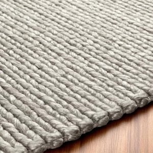 Op de afbeelding: Close-up van een lichtgrijs, handgeknoopt tapijt. Het tapijt heeft een dikke, getextureerde weefsel met zichtbare knopen en een zacht, neutraal kleurenpalet. Het ontwerp van het tapijt is eenvoudig en elegant, geschikt voor diverse interieurstijlen.