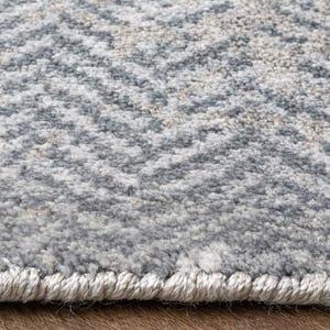May include: Close-up of a textured area rug with a repeating chevron pattern. The rug features a blend of gray, off-white, and beige tones, creating a neutral color palette. The edges are finished with a light-colored border.