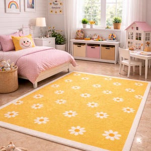 May include: A yellow rectangular rug with white daisy flower patterns and a white border. The rug is in a child's bedroom with a pink bedspread, a white nightstand, and a dollhouse. The room has a bright and cheerful atmosphere.