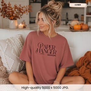 Pode incluir: Uma t-shirt de manga curta em rosa seco com o texto preto "PAPER HANGER MOCKUPS" estampado na frente. A pe&ccedil;a tem gola redonda e um corte descontra&iacute;do, feita de tecido de cor s&oacute;lida com textura lisa e costuras vis&iacute;veis.