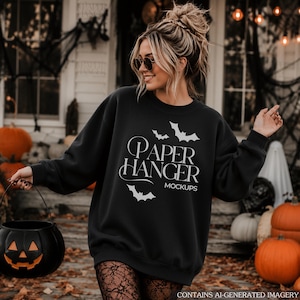 Könnte beinhalten: Ein schwarzes Langarm-Sweatshirt mit Rundhalsausschnitt und weißem Schriftzug PAPER HANGER MOCKUPS, ergänzt durch weiße grafische Illustrationen von fliegenden Fledermäusen, die über und unter dem zentralen Schriftzug auf der Vorderseite platziert sind.