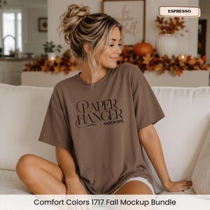 Pode incluir: Uma t-shirt castanha de manga curta com o texto preto "PAPER HANGER MOCKUPS" estampado no peito. A pe&ccedil;a tem gola redonda e um corte descontra&iacute;do, com uma etiqueta no canto superior direito da imagem exibindo a palavra "ESPRESSO".