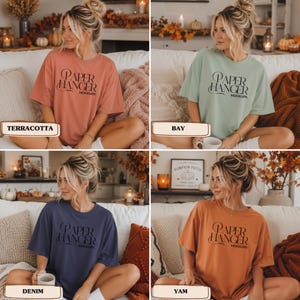 Pode incluir: Uma cole&ccedil;&atilde;o de quatro camisetas de manga curta e gola redonda nas cores terracota, bay, denim e yam. Cada camiseta apresenta o texto preto "PAPER HANGER MOCKUPS" estampado no peito em uma fonte serifada estilizada com uma elegante letra P.