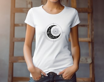 May include: White t-shirt with a black and white graphic of a crescent moon with a sun and eye inside. The moon is surrounded by stars.