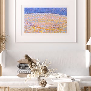 Può includere: Un dipinto astratto incorniciato con uno schema di colori blu, giallo e rosa. Il dipinto è esposto su una parete bianca sopra un divano bianco con cuscini.