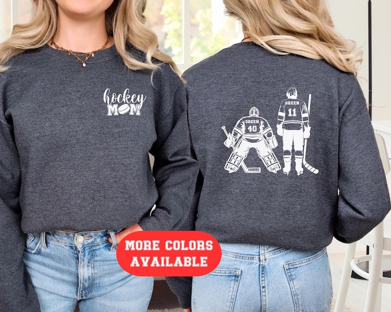 May include: A dark grey sweatshirt with the text "hockey mom" and a hockey puck graphic on the front. The back of the sweatshirt features a white graphic of two hockey players, one wearing number 40 and the other wearing number 11.