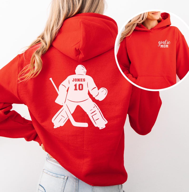 Op de afbeelding: Een rode hoodie met een witte hockey goalie graphic op de rug, met de naam "JONES" en het nummer "10". De voorkant van de hoodie heeft de tekst "goalie MOM" in het wit.
