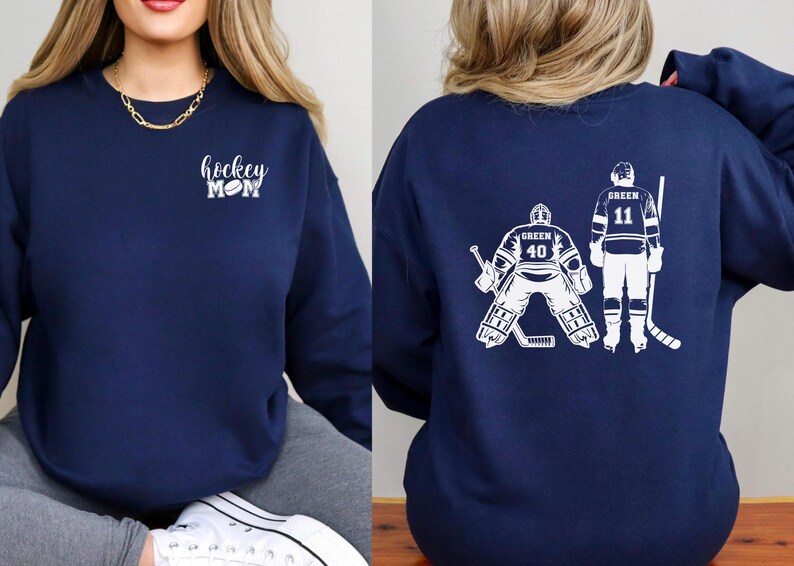 May include: Two navy blue sweatshirts. One sweatshirt has the text "hockey mom" with a hockey puck on the left chest. The other sweatshirt has a white graphic of two hockey players on the back. One player is a goalie with the number 40 and the other player has the number 11.