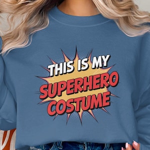 May include: A blue sweatshirt with a white and red graphic that says "This is my superhero costume".