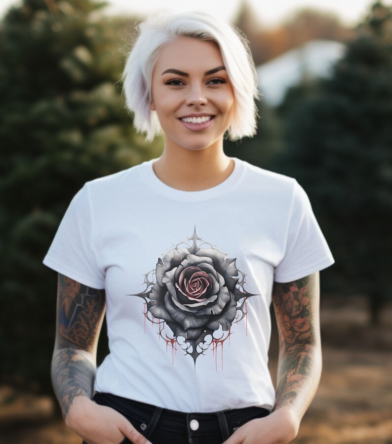 May include: White t-shirt featuring a black and grey rose graphic with red dripping accents. The rose is surrounded by a black and grey intricate design.
