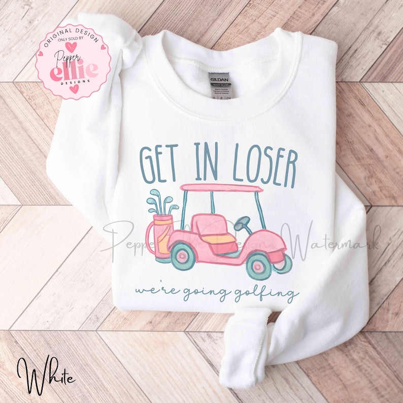 Puede incluir: Sudadera blanca con la frase "GET IN LOSER" sobre una ilustraci&oacute;n de un carrito de golf rosa. Debajo, el texto dice "we're going golfing". La sudadera tiene mangas largas y cuello redondo.