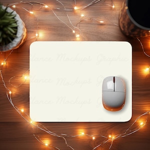 May include: A white mouse pad with a white wireless mouse on top of it. The mouse pad is on a wooden surface with a string of white lights around it.