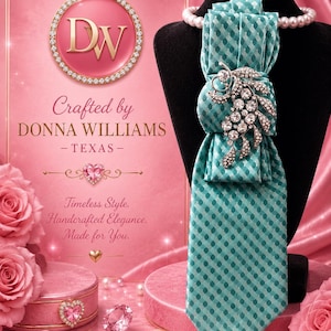 May include: A teal and white gingham necktie featuring a silver-toned leaf-shaped brooch adorned with clear crystals. The tie is displayed on a black mannequin neck form, accented by a string of white pearls around the collar area.